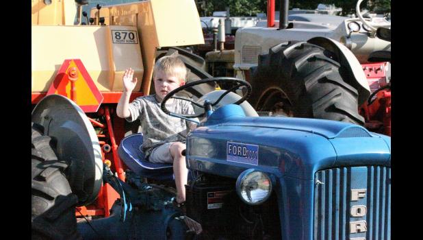 Photo by Paul Hettinger Three-year old Zander Smith tries a Ford tractor on for size.