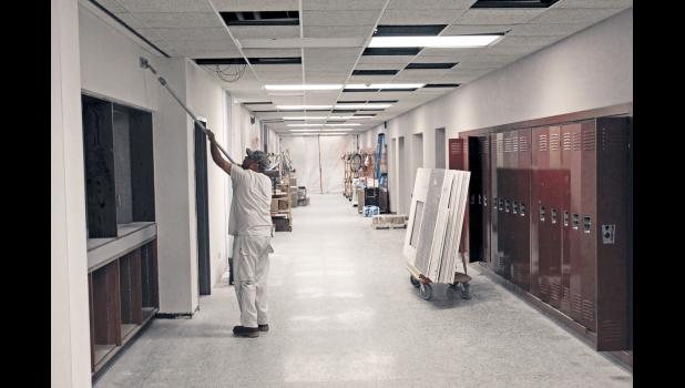 A member of the construction crew puts finishing touches on new drywall.