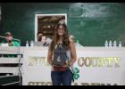 4-H Achievement Royalty Scarlett Browning auctions off a golf-themed gift basket.